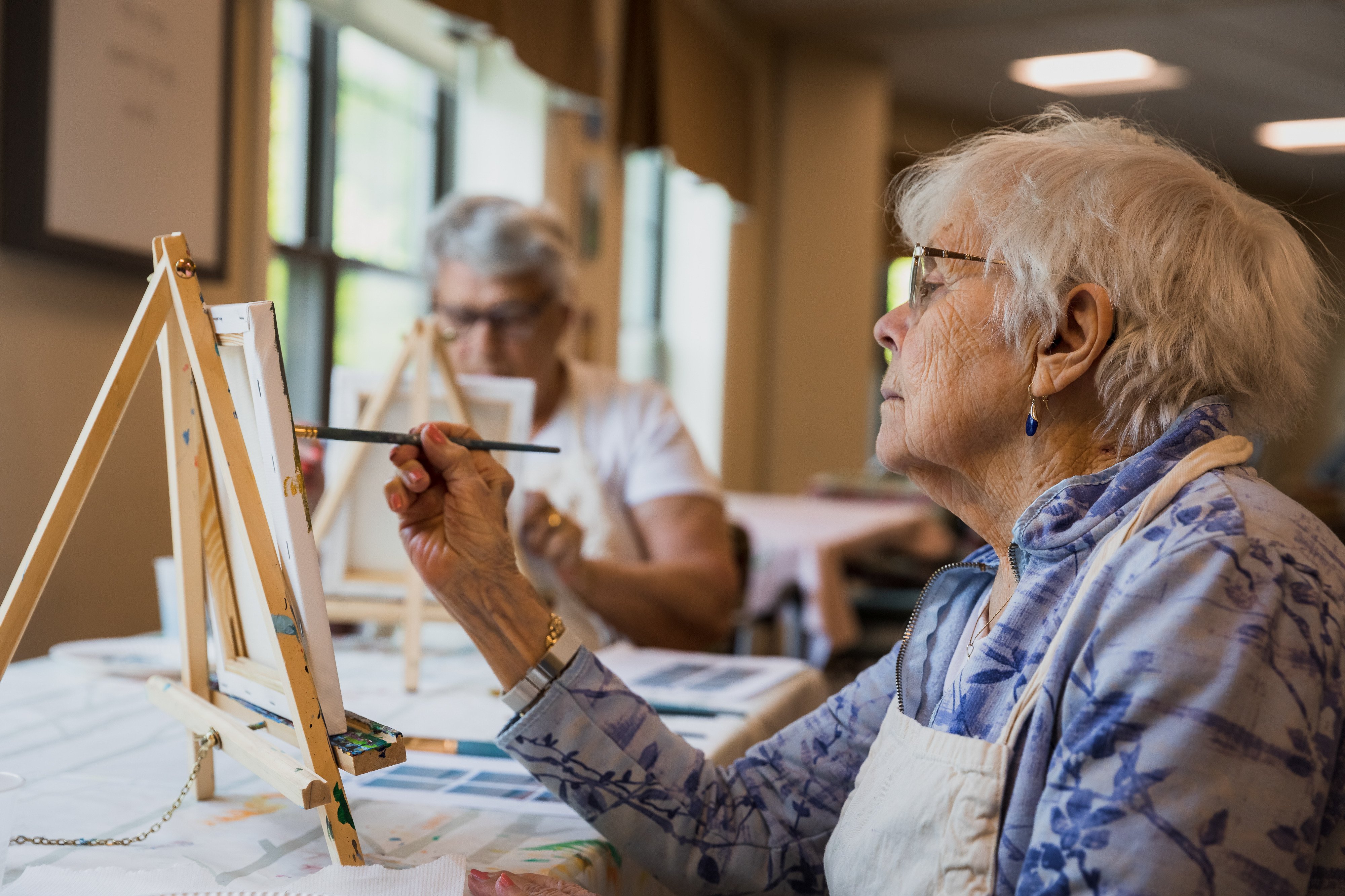 Elderly women painting on a canvas 