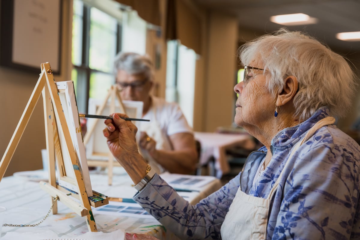 Elderly women painting on a canvas 